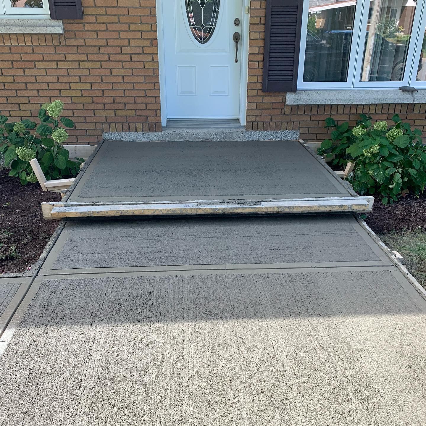 Une maison en briques avec une allée en béton menant à la porte d'entrée.