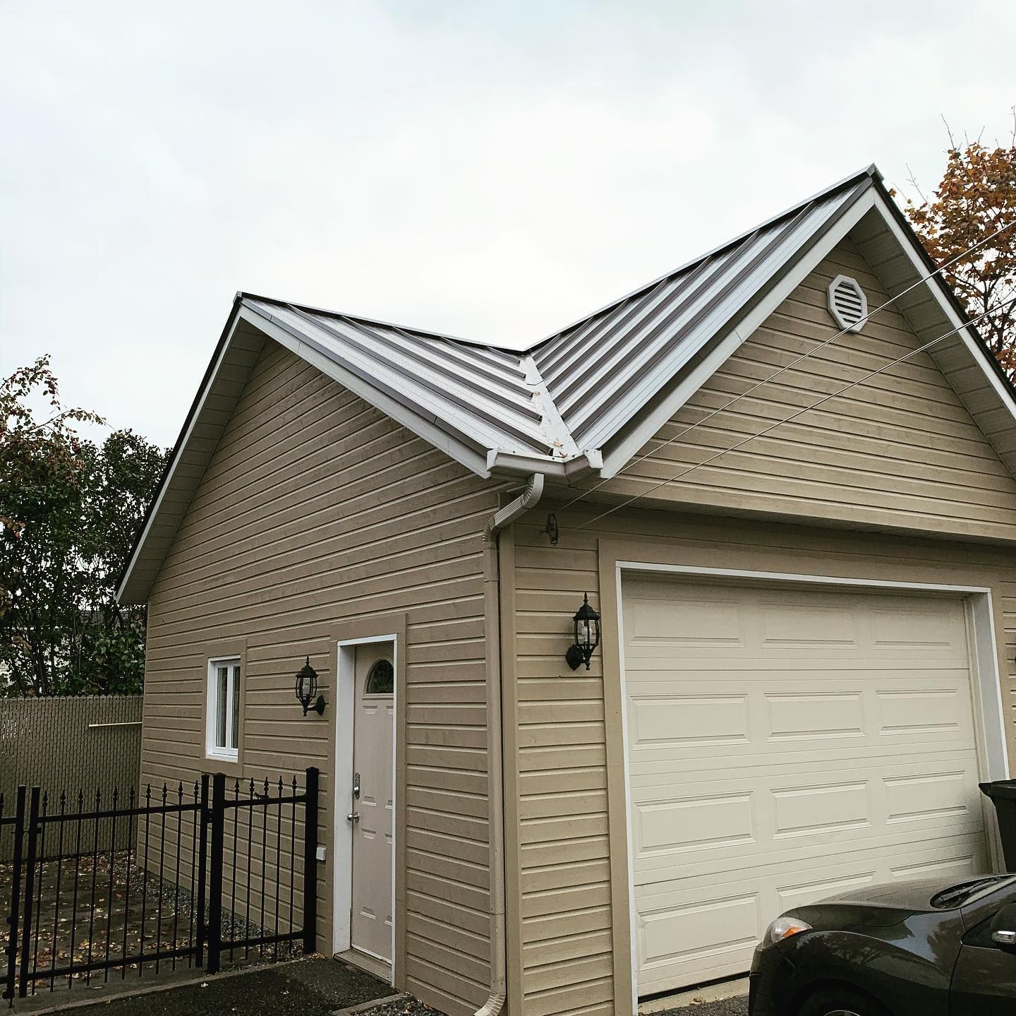Une voiture est garée devant un garage avec un toit en métal.