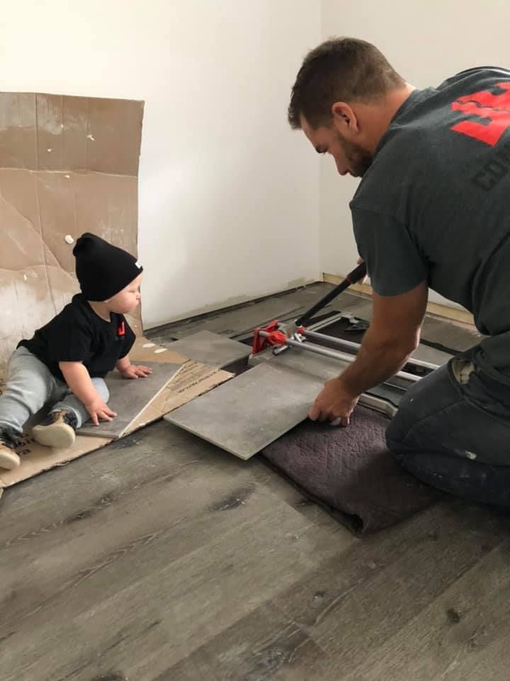 Un homme et un bébé sont agenouillés sur le sol.