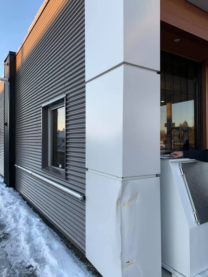 Une personne se tient devant un bâtiment avec de la neige au sol