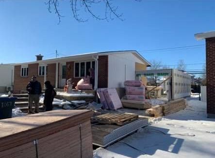 Un groupe de personnes se tient devant une maison en cours de rénovation.