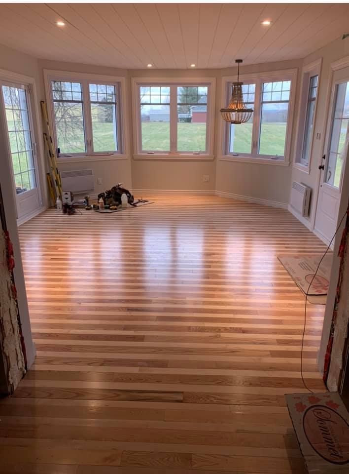 Une pièce avec un plancher en bois et beaucoup de fenêtres.