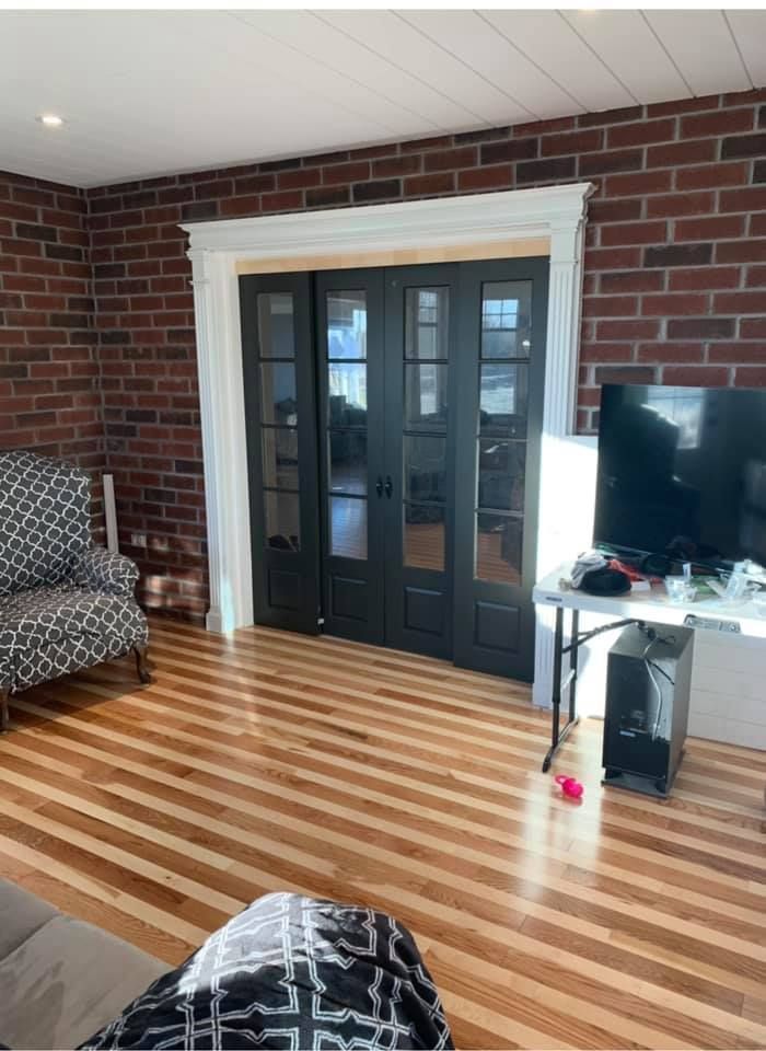 Un salon avec du parquet et un mur de briques