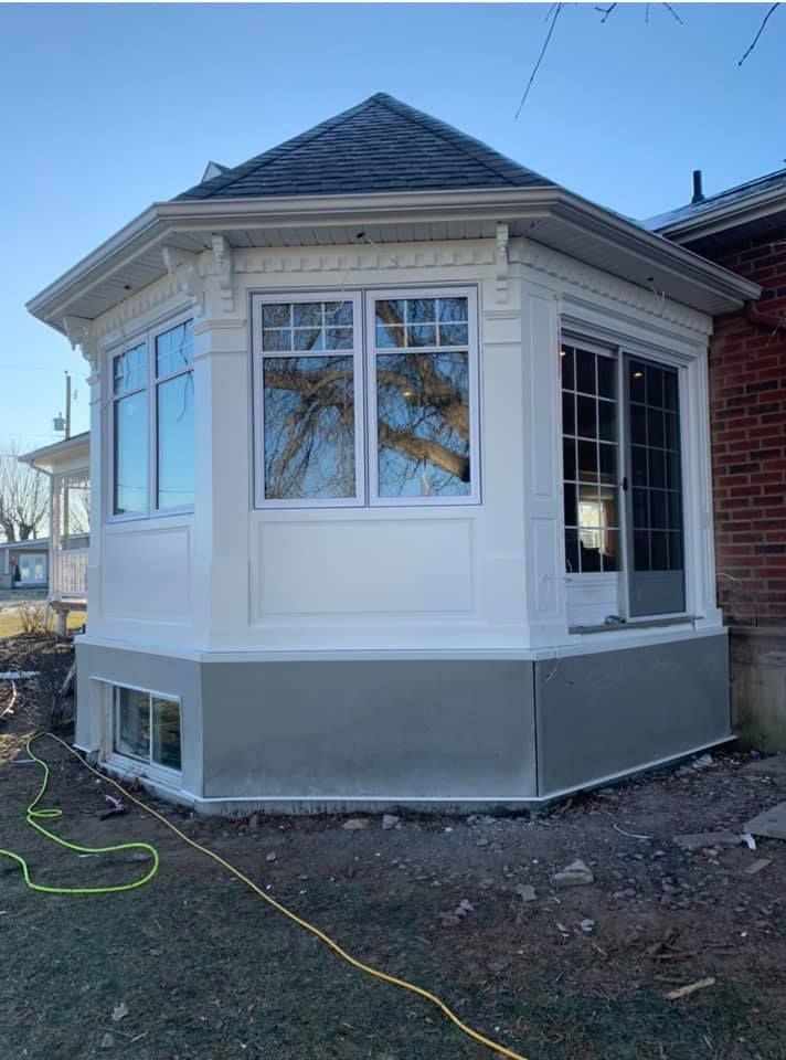 Une maison blanche avec une grande fenêtre sur le côté.