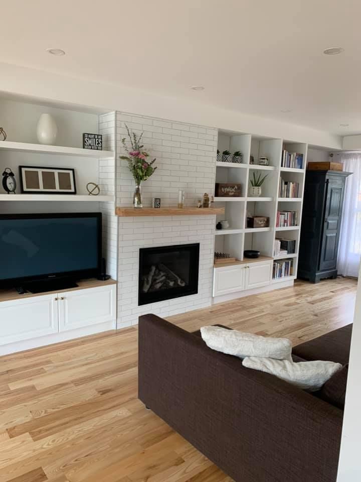 Un salon avec cheminée, canapé, télévision et étagères.