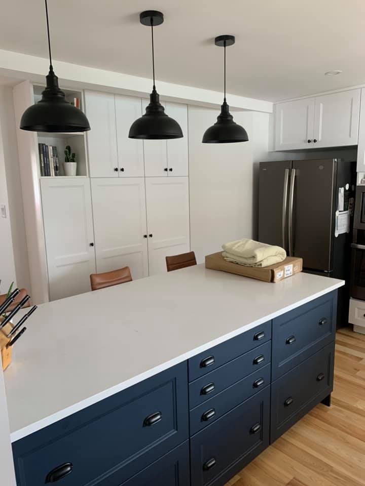 Une cuisine avec des armoires bleues et des comptoirs blancs et un grand îlot.