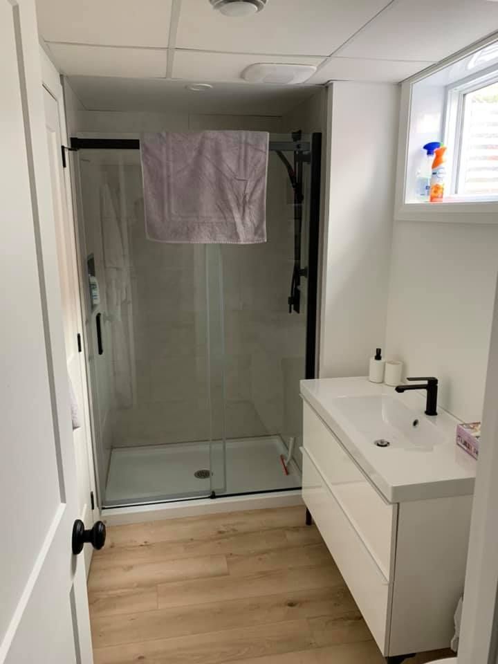 Une salle de bain avec lavabo, douche et fenêtre.