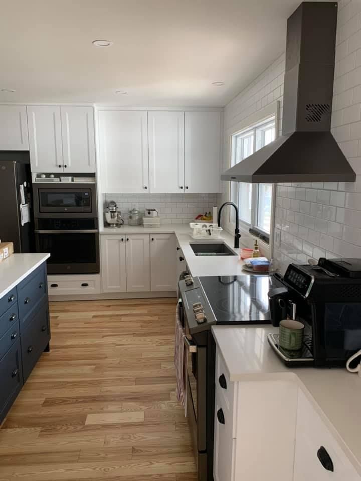 Une cuisine avec des armoires blanches, des appareils en acier inoxydable, un évier et une cuisinière.