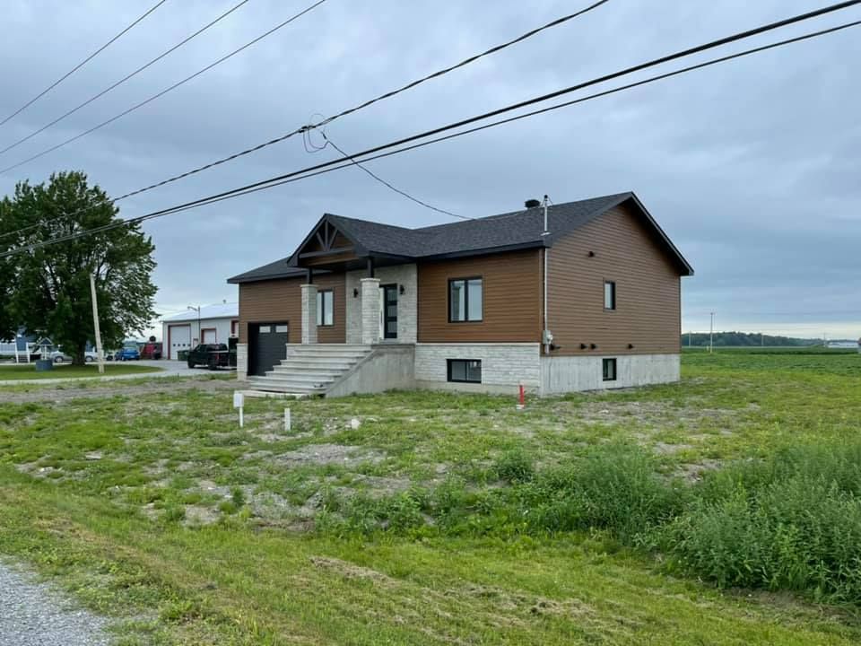 Une maison est située au milieu d'un champ herbeux.