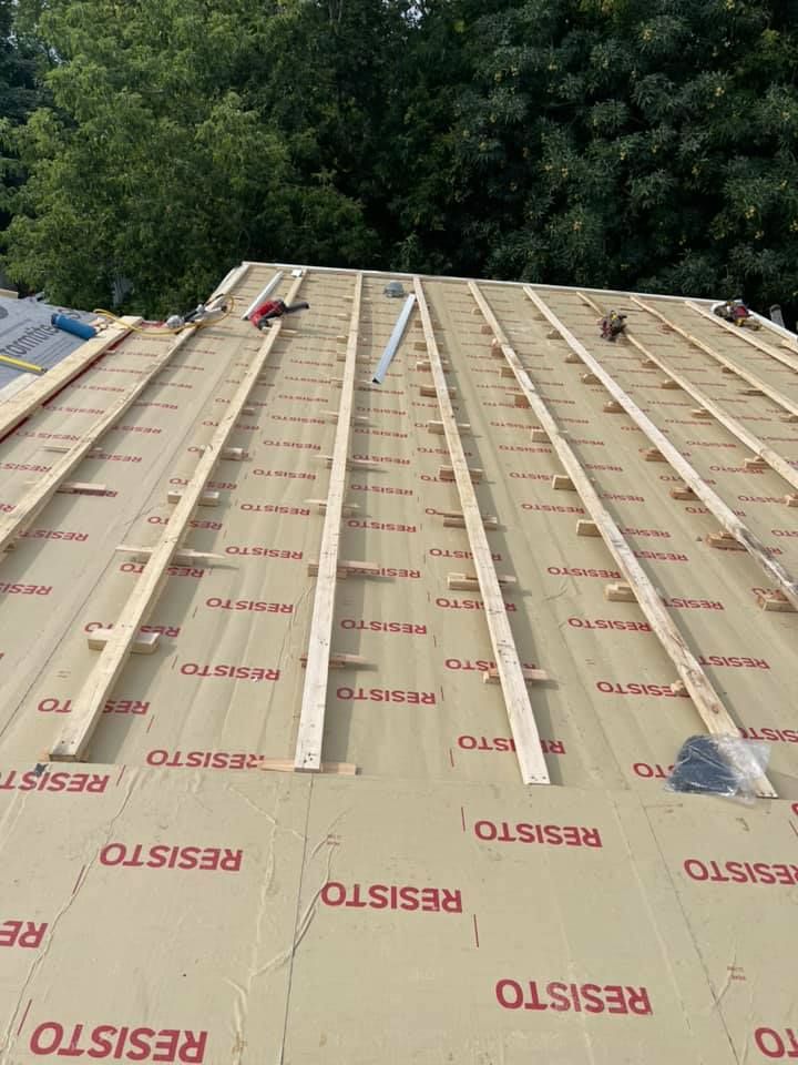 Un toit est en cours de construction avec des poutres en bois.