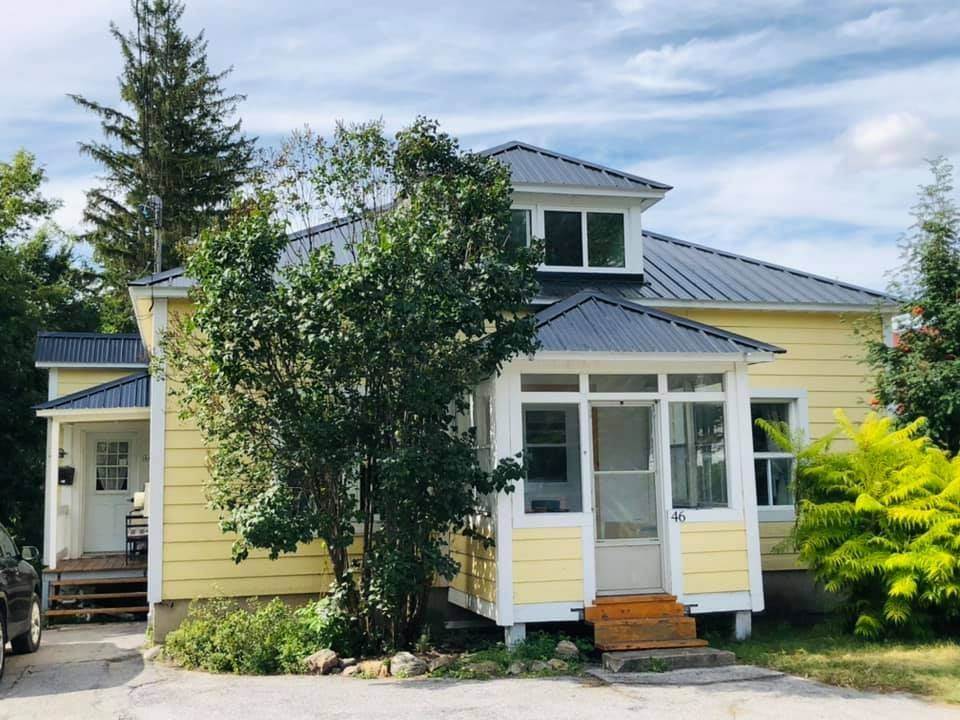 Une maison jaune avec un toit bleu et une voiture garée devant