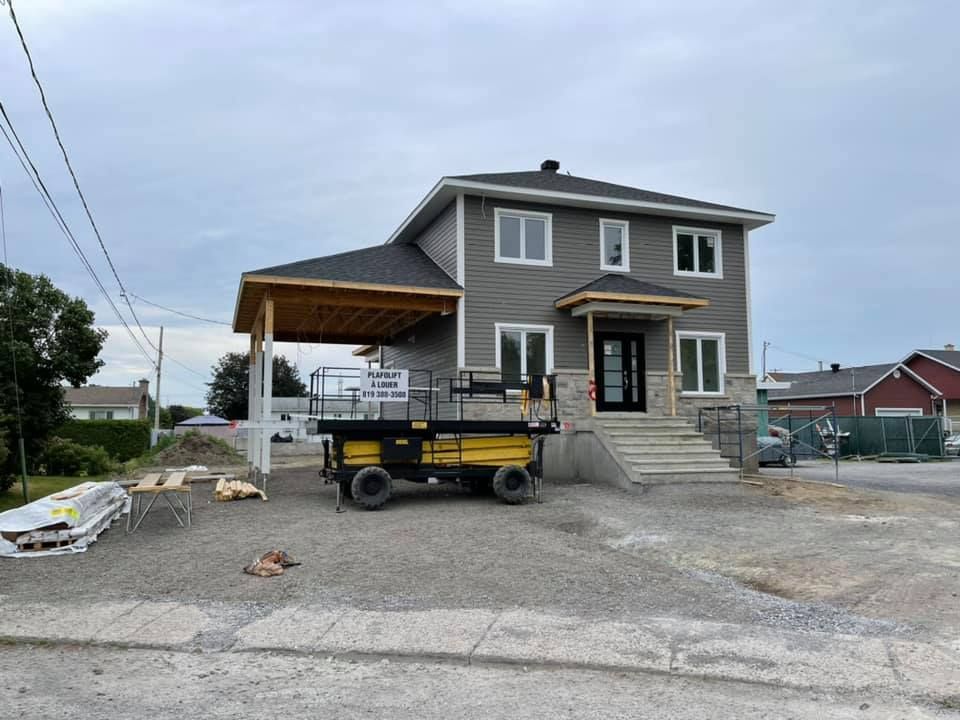 Une grande maison en construction avec un ascenseur jaune devant.