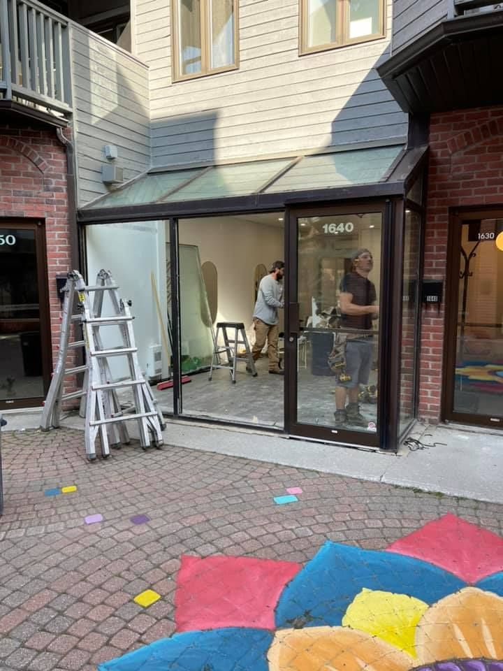 Un groupe de personnes travaille sur une porte vitrée à l'extérieur d'un bâtiment.