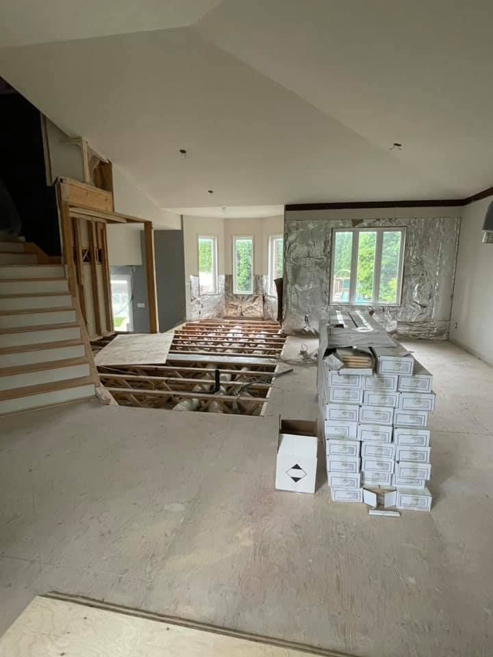 Une grande pièce avec beaucoup de boîtes au sol et des escaliers.