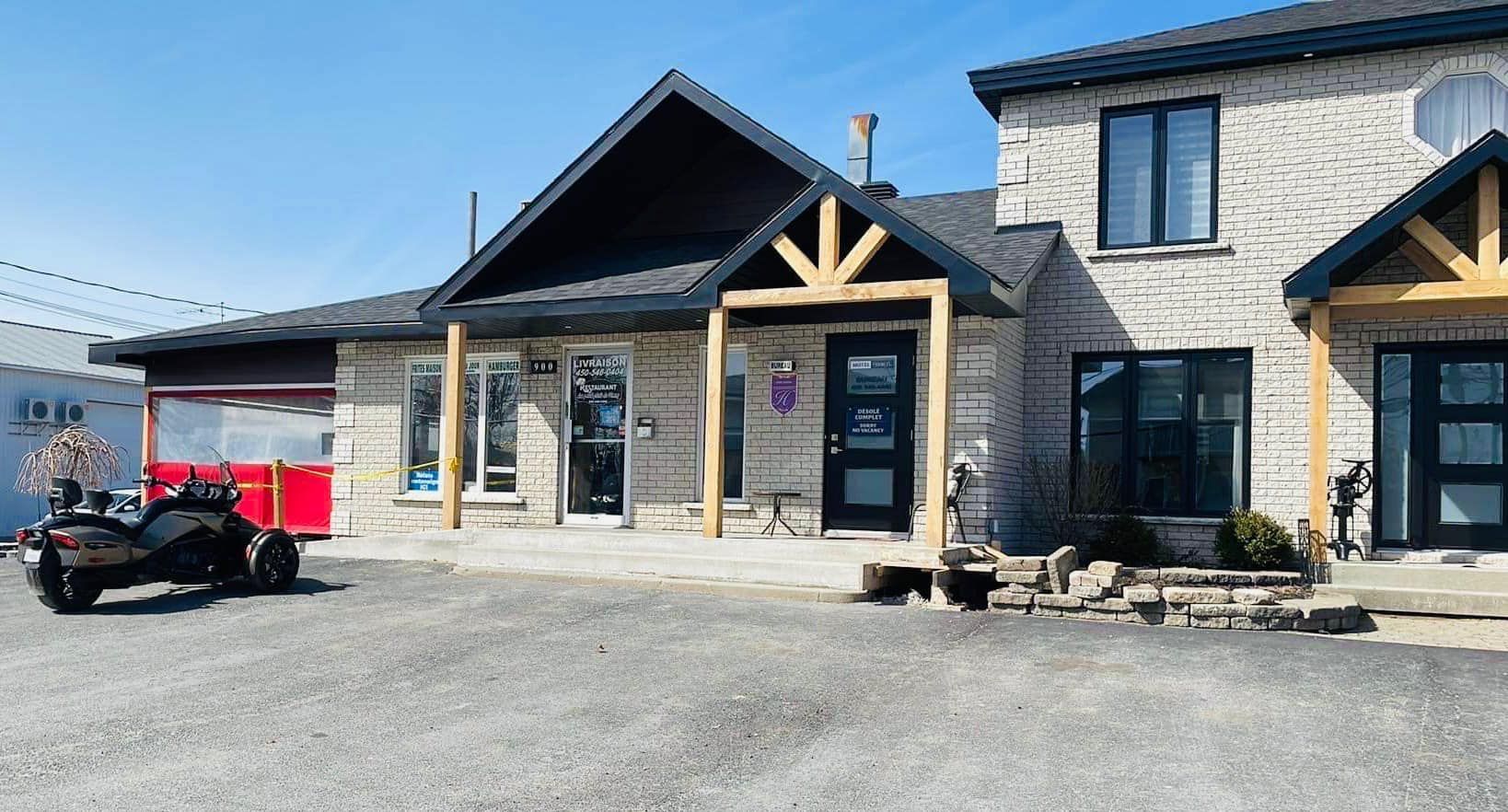 Une maison avec une caravane rouge garée devant.