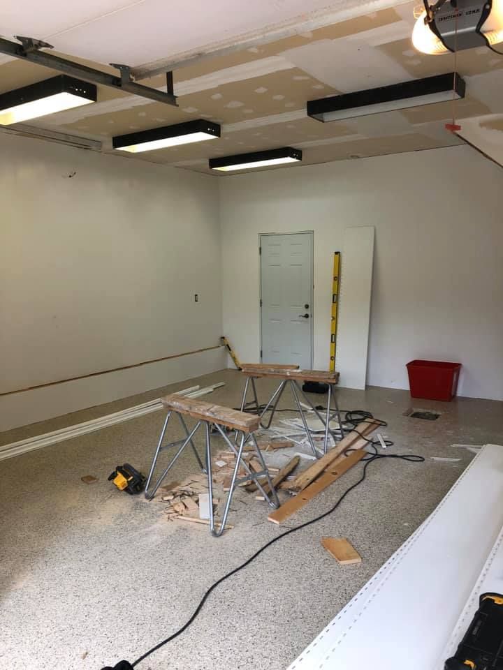 Un garage est en cours de rénovation avec beaucoup d'outils au sol.