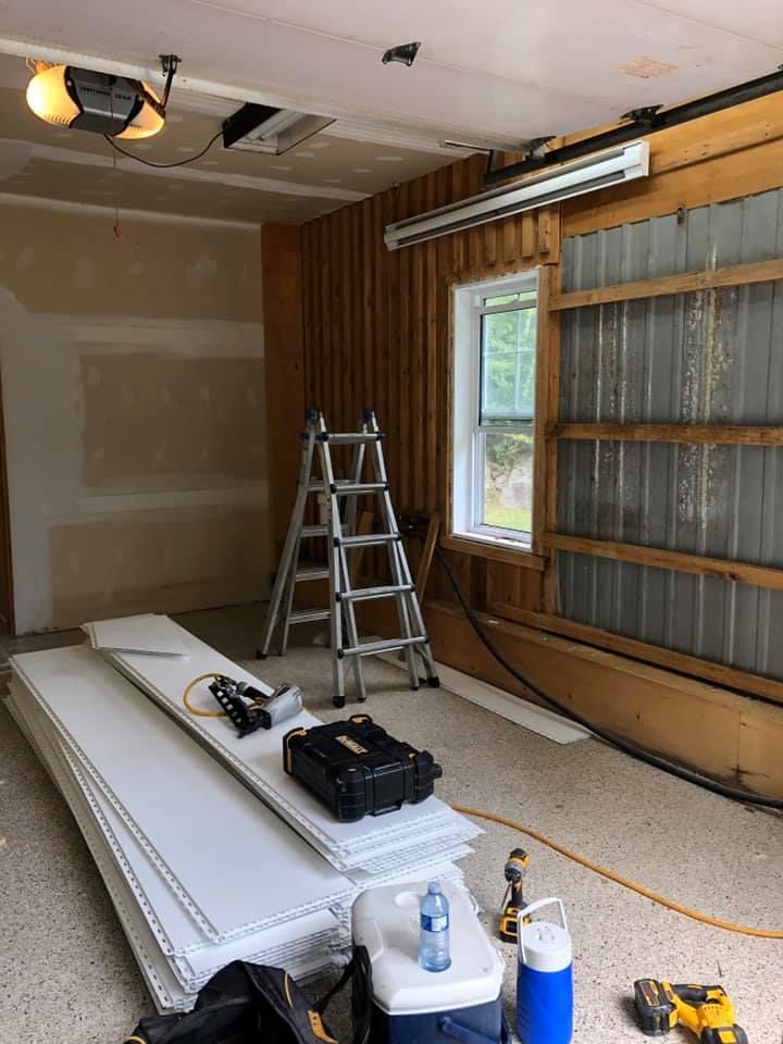 Un garage est en cours de rénovation avec une échelle et une glacière.