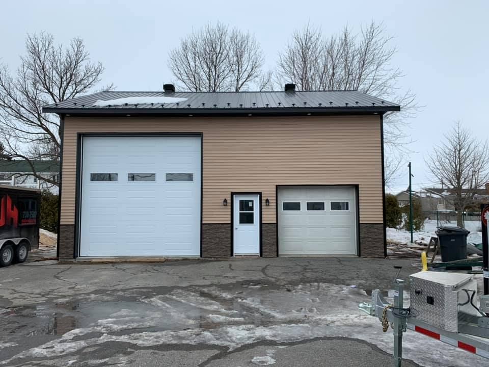 Un grand garage avec deux portes de garage et une remorque garée devant.