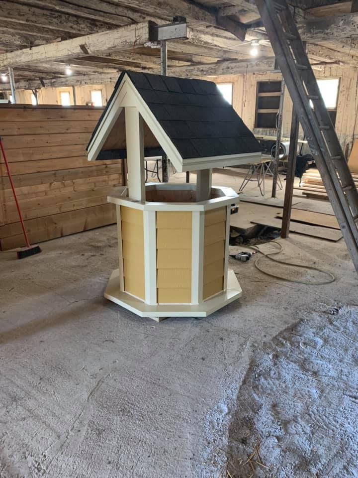 Un puits jaune et blanc avec un toit noir se trouve dans une pièce.