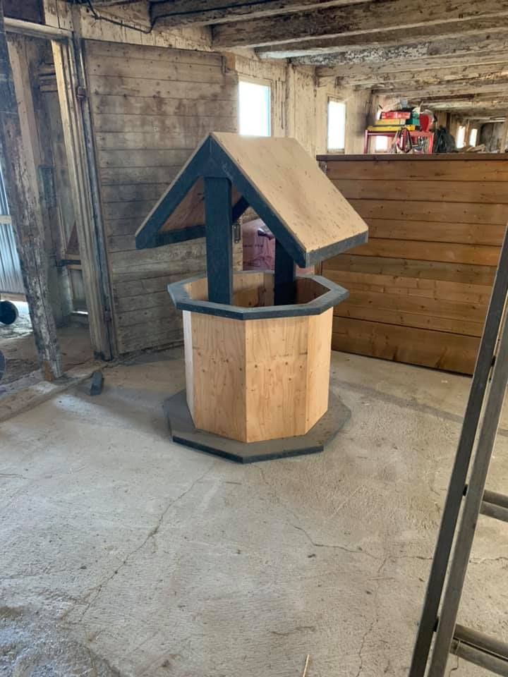 Un puits à souhaits en bois se trouve dans une pièce à côté d'une échelle.