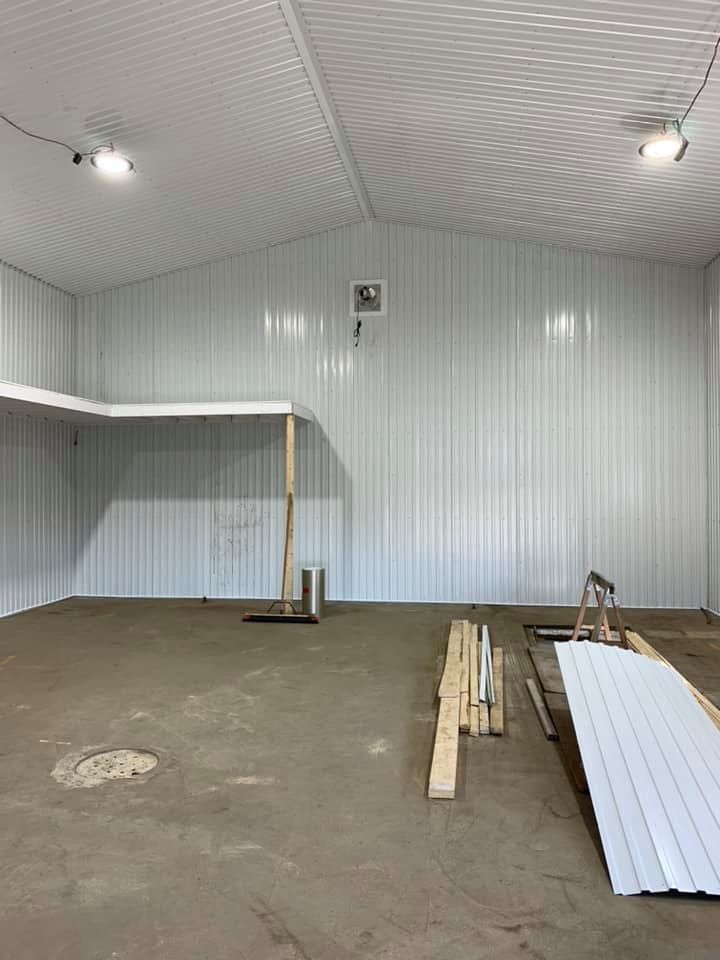 Un grand bâtiment vide avec des murs blancs et un ventilateur au plafond.