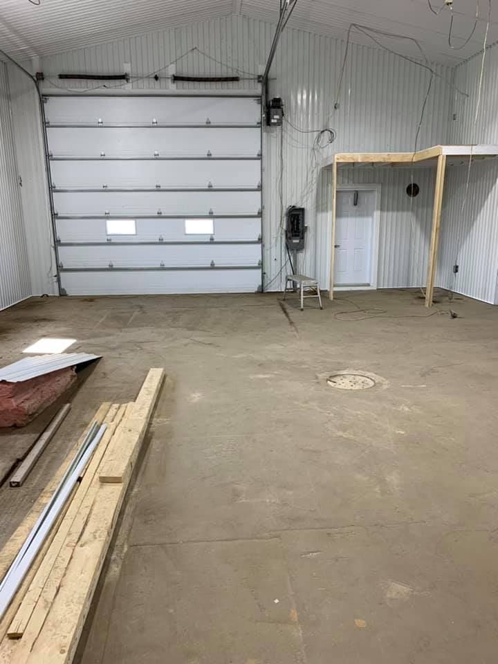 Un garage avec une grande porte de garage et un plancher en bois.