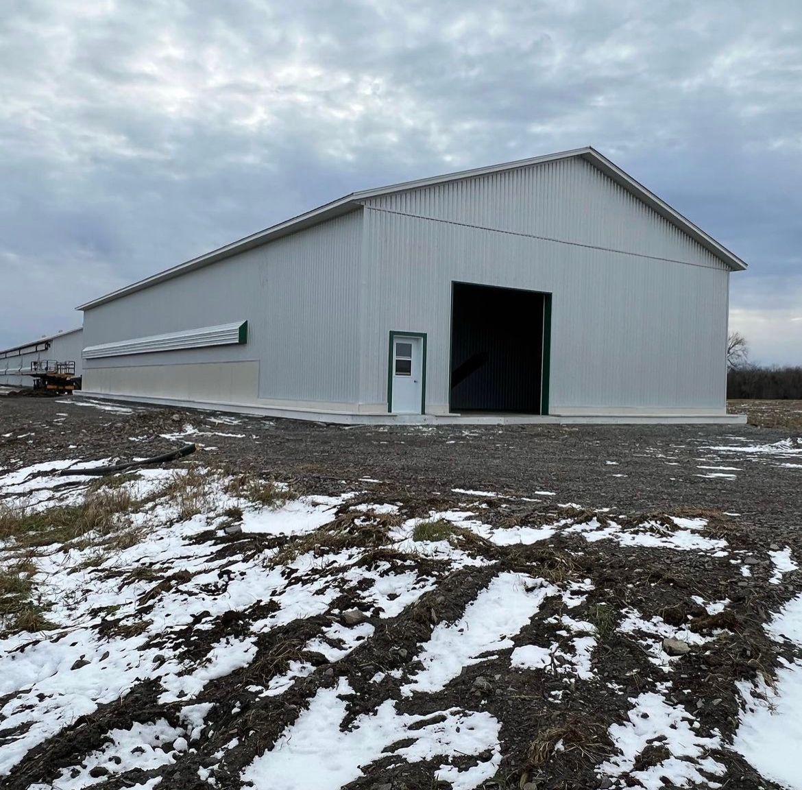 Une grande grange blanche se trouve au milieu d'un champ enneigé
