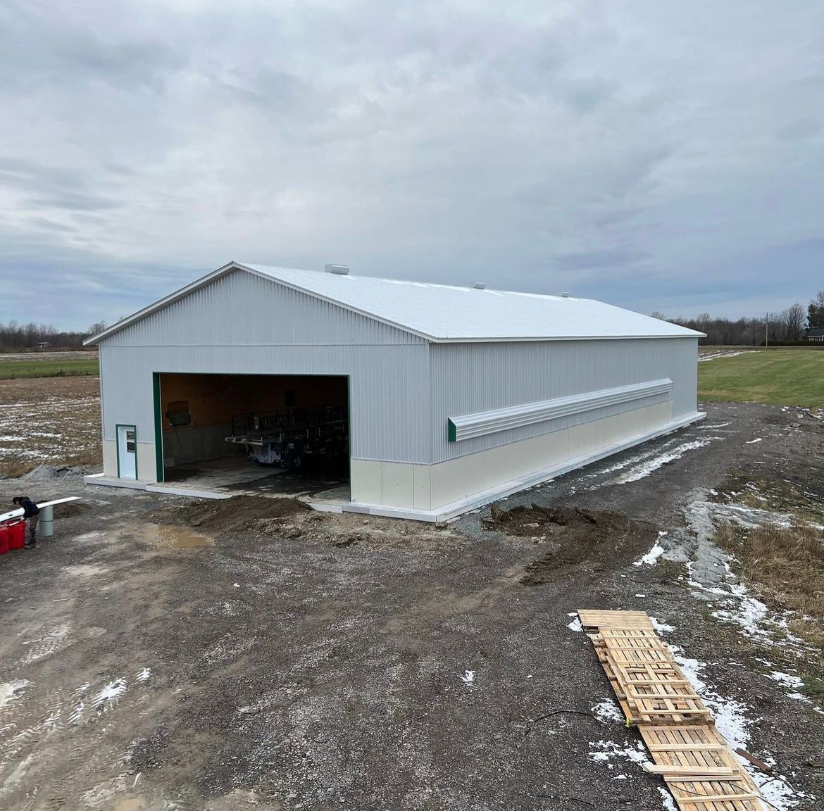 Un grand bâtiment en métal blanc se trouve au milieu d'un champ de terre.