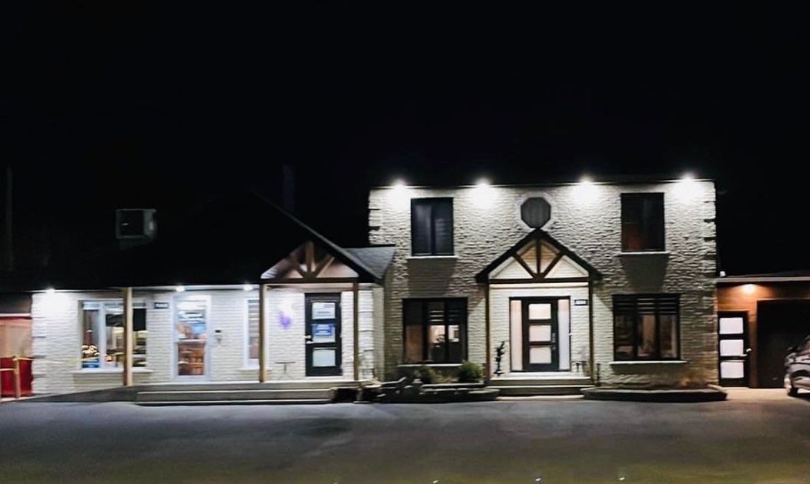 Une grande maison avec beaucoup de fenêtres est éclairée la nuit.