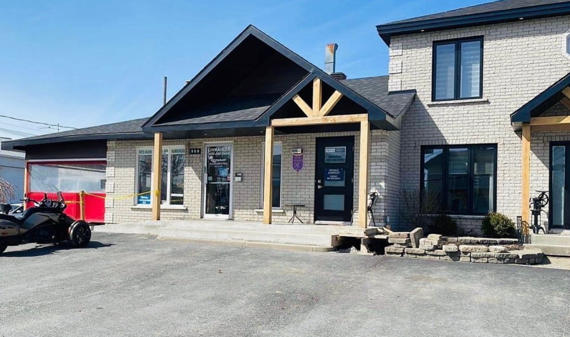 Une grande maison en briques avec un porche et un VTT garé devant.