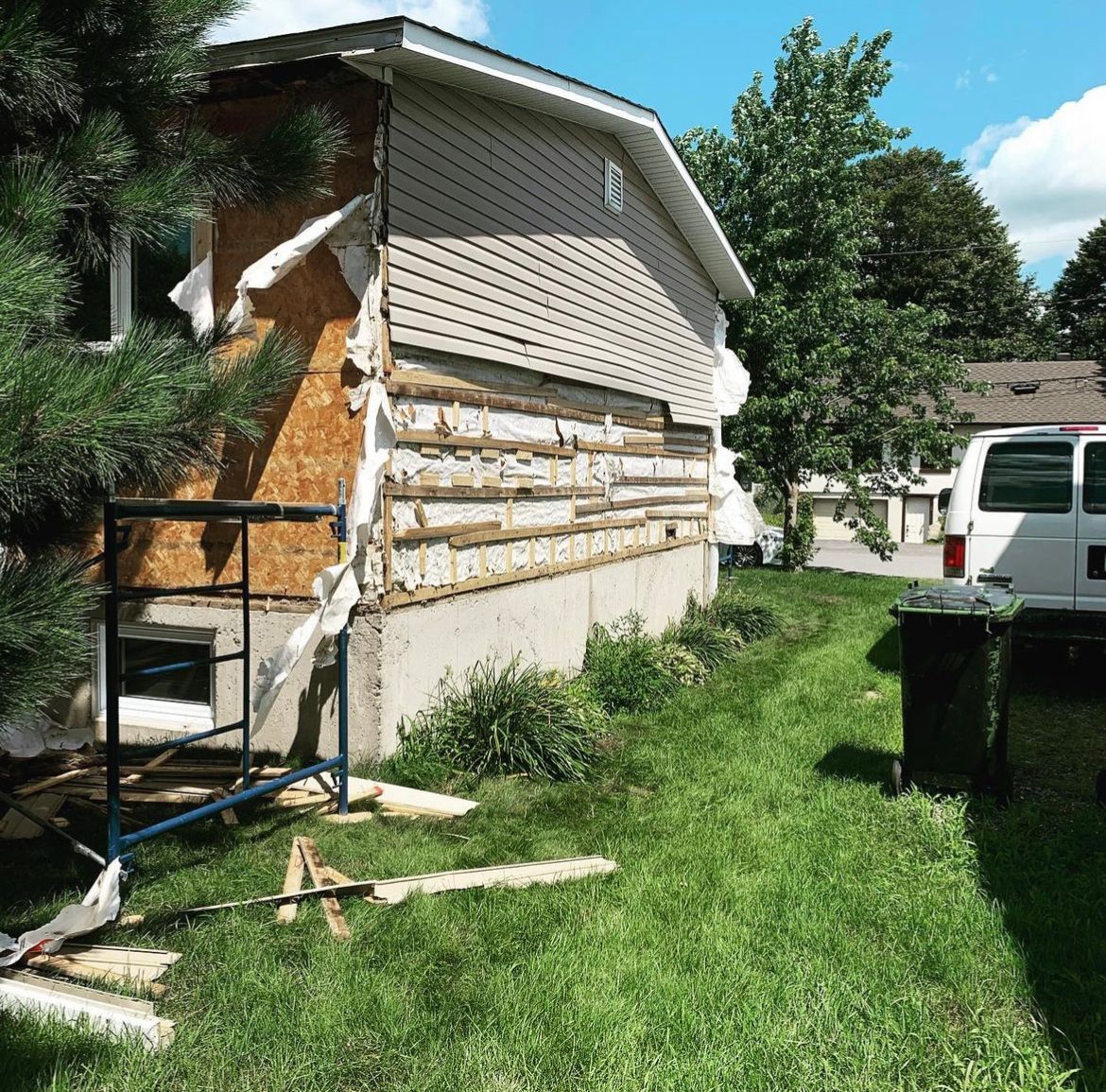 Une camionnette blanche est garée devant une maison en cours de démolition
