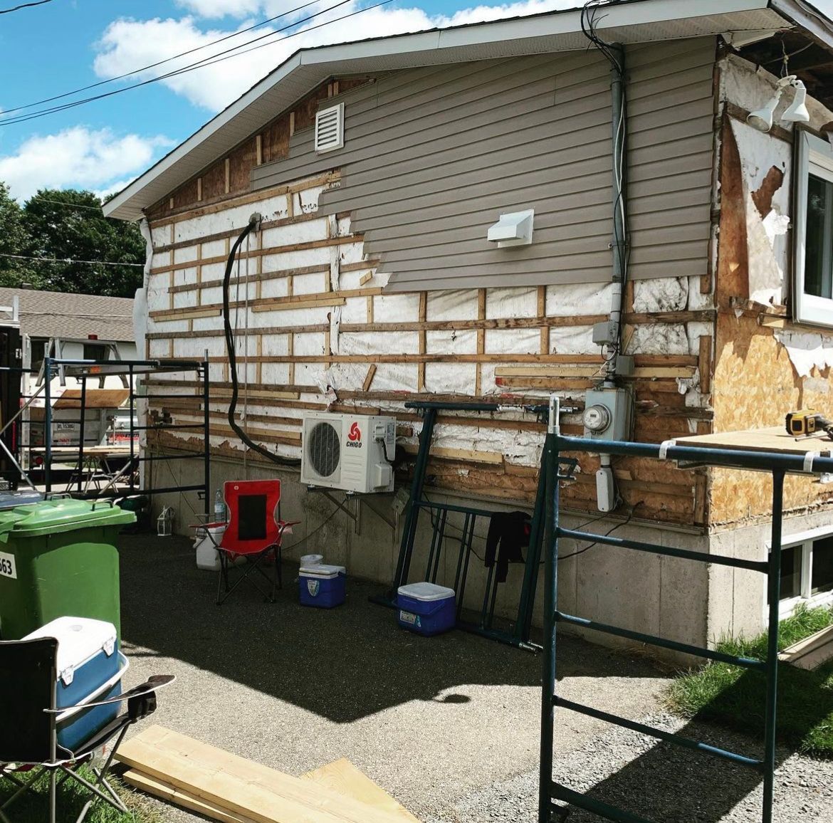 Une maison en cours de rénovation avec quelques glacières devant