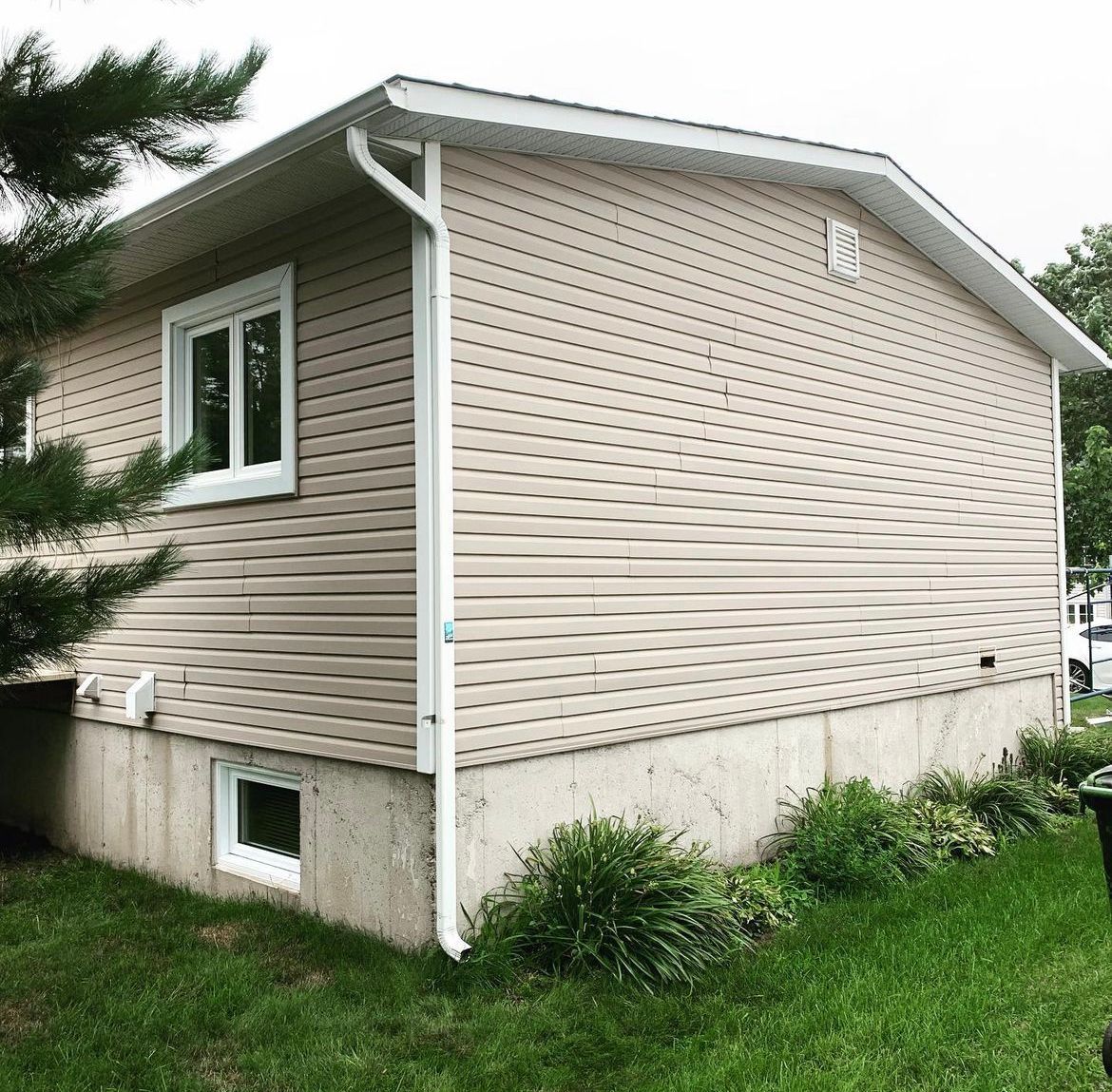 Une petite maison avec beaucoup de fenêtres est assise dans l'herbe.