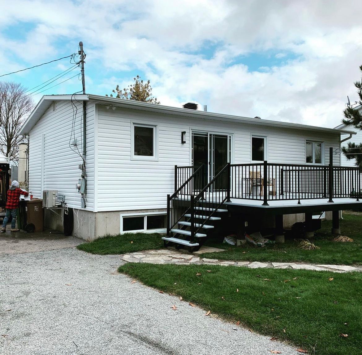 Une maison blanche avec une terrasse et des escaliers noirs
