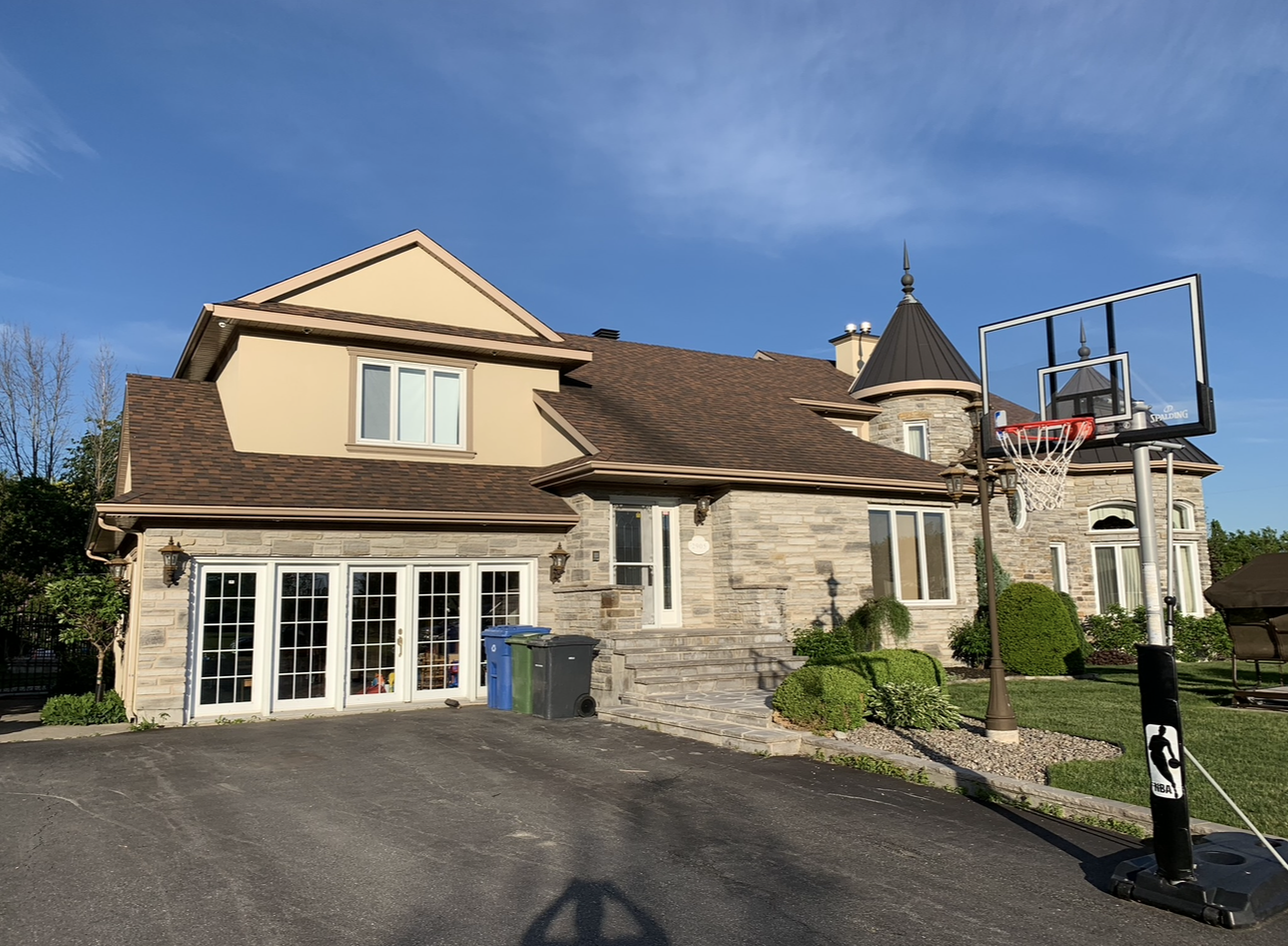 Une grande maison avec un panier de basket devant.