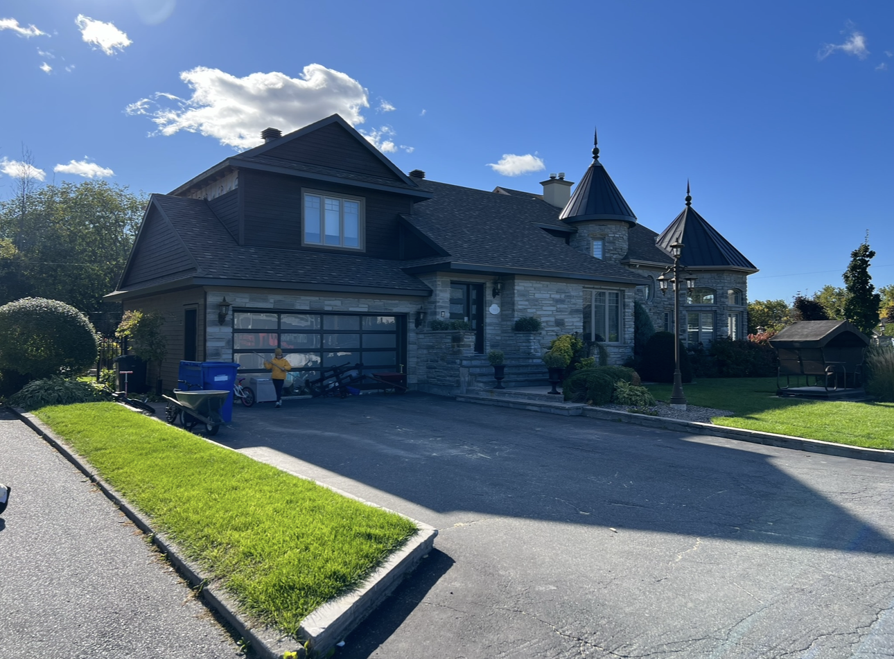 Une grande maison avec un toit de château et une grande allée