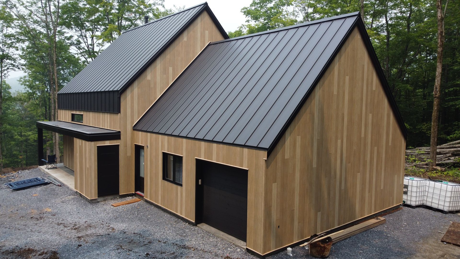 Une maison en bois avec un toit noir est entourée d'arbres.