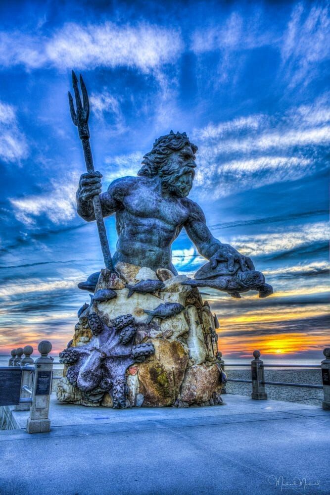 a statue of a man holding a trident on top of a rock