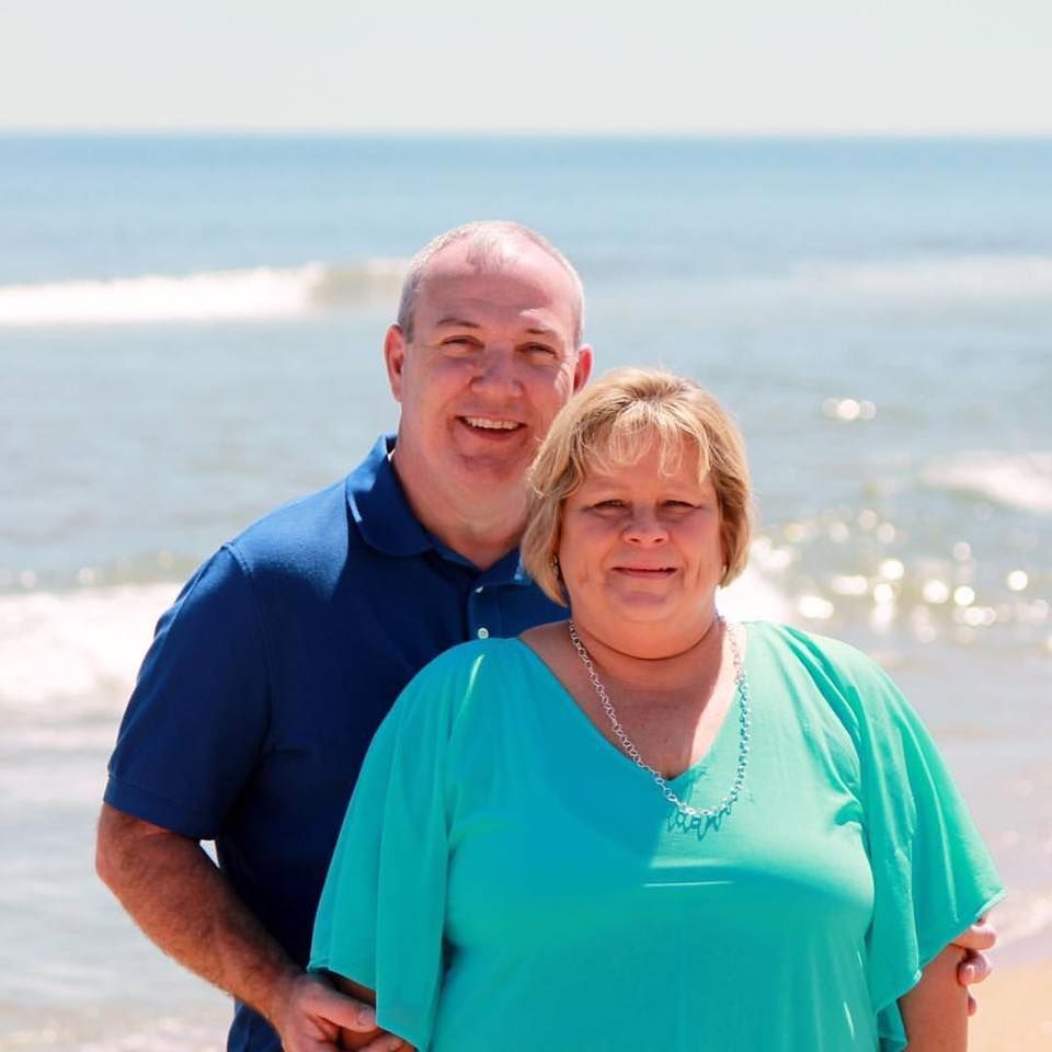 A man and woman are posing for a picture on the beach