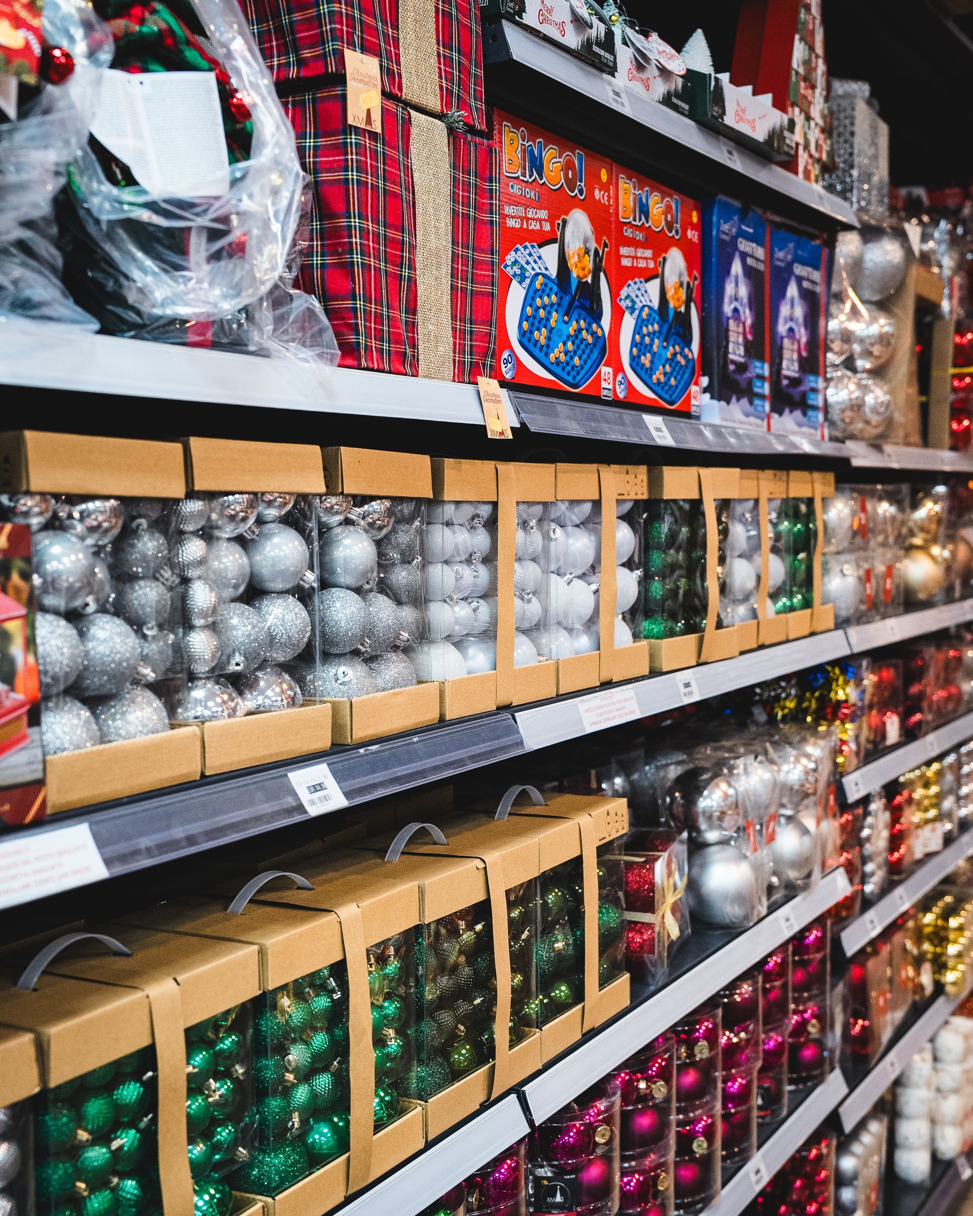 Scaffali pieni di decorazioni natalizie di vari colori e stili, esposte in scatole.