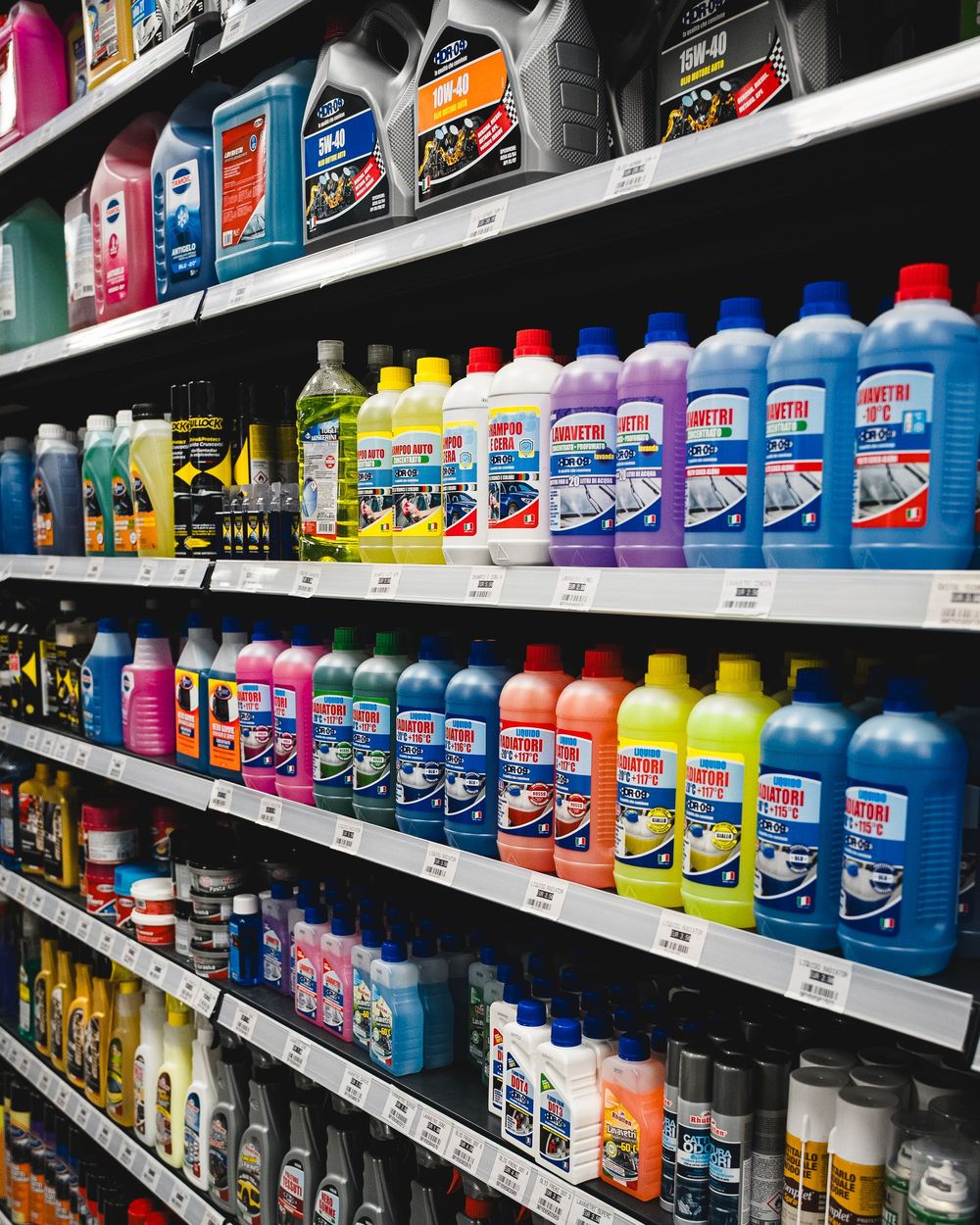 Scaffali pieni di bottiglie colorate di liquidi per auto in un negozio.