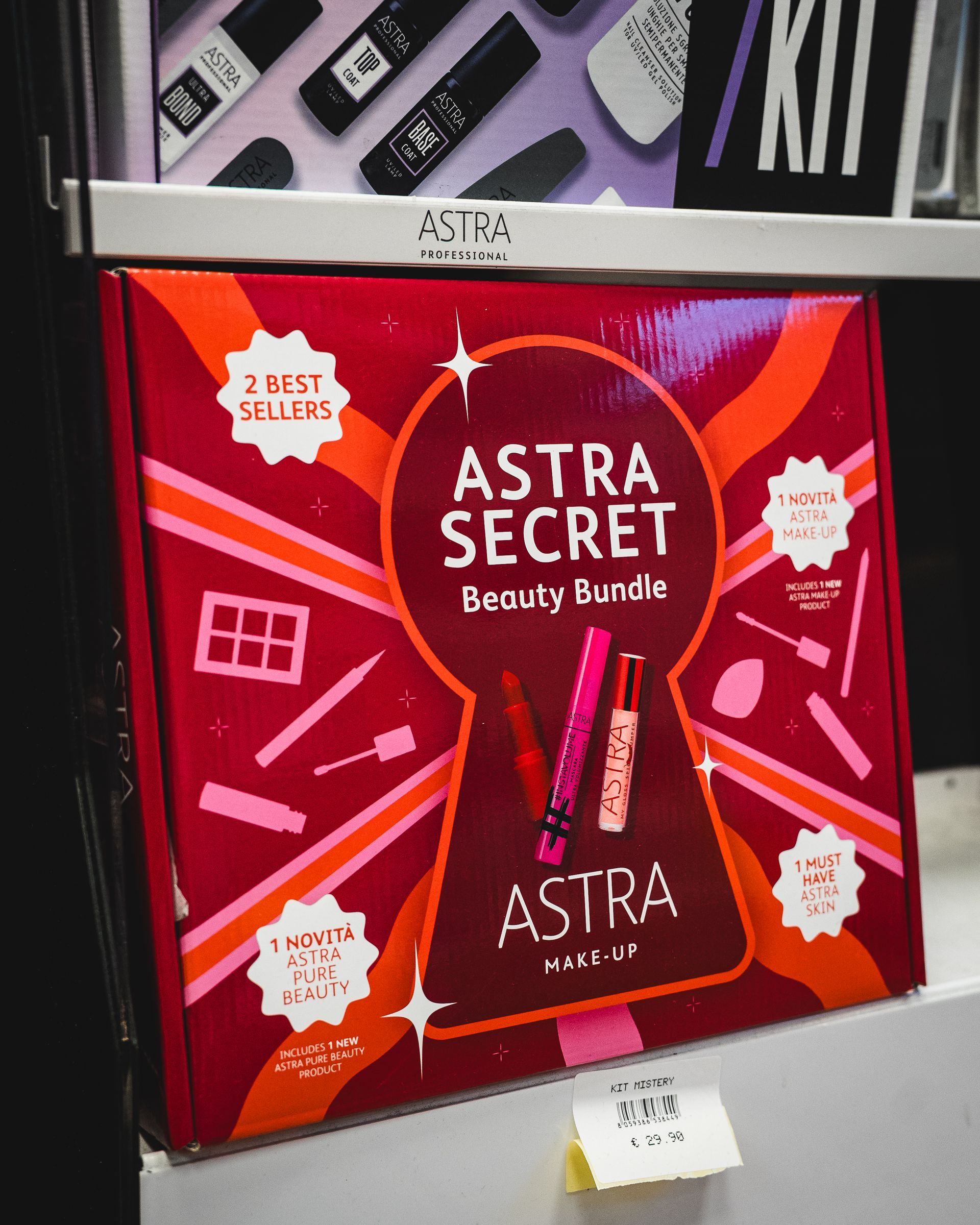 Un set regalo rosso Astra Secret Beauty Bundle sullo scaffale di un negozio, con un design a forma di buco della serratura e illustrazioni di prodotti per il trucco.