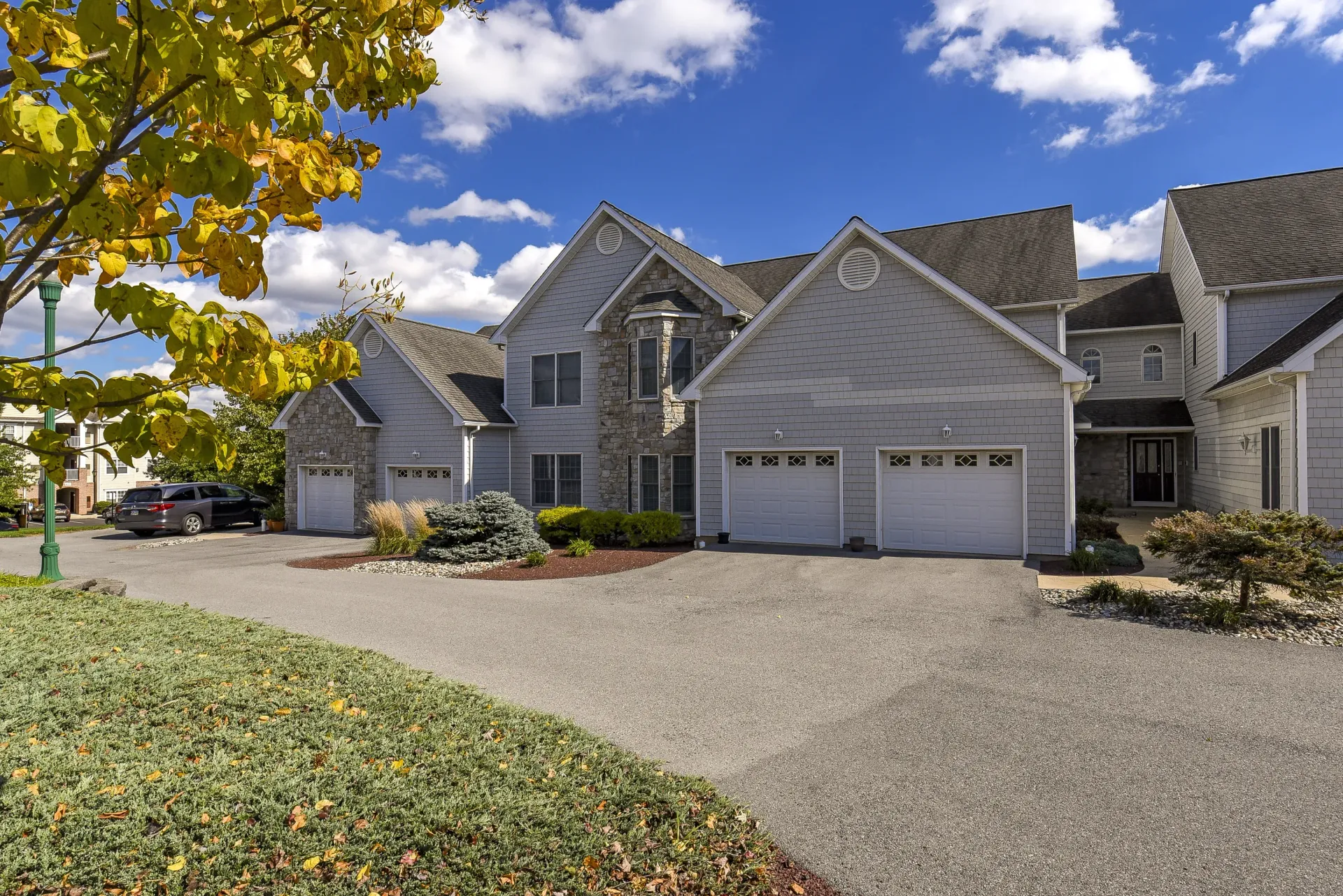 Exterior view of a townhouse-style apartment building with attached garages and landscaping at Springhouse Townhomes in Allentown, PA.
