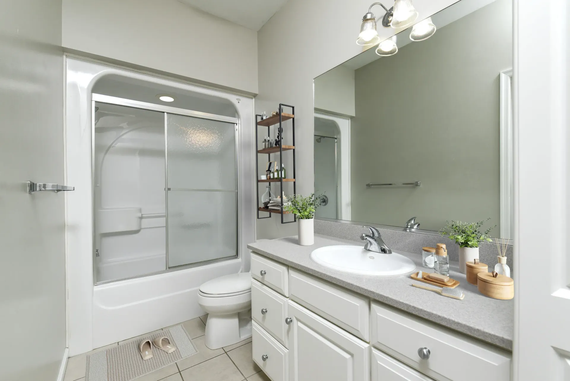 Bright bathroom with white vanity, sink, large mirror, shelving, and sliding shower doors at Springhouse Townhomes in Allentown, PA.