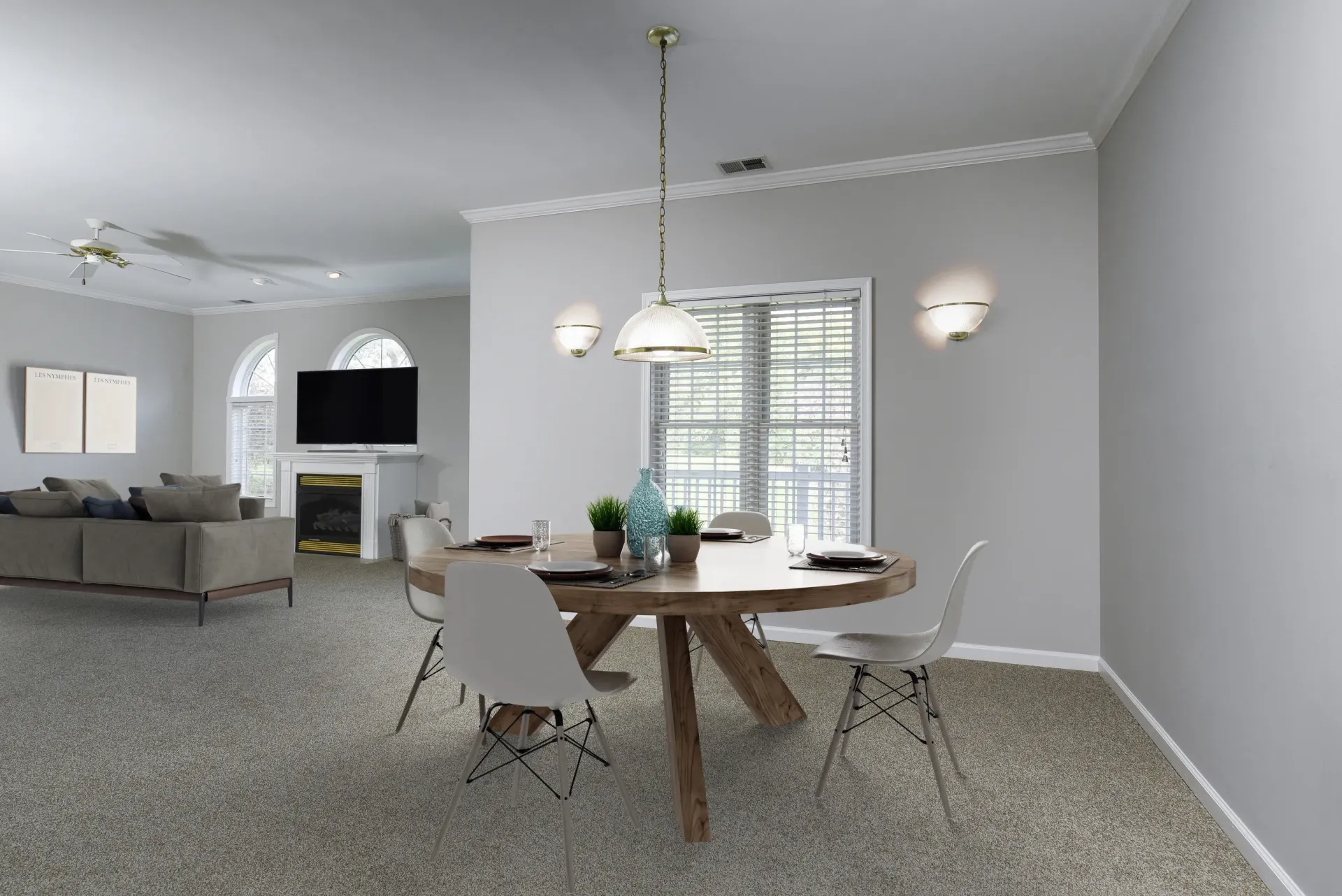 Open living and dining area of an apartment with a round wooden table and white chairs at Springhouse Townhomes in Allentown, PA.