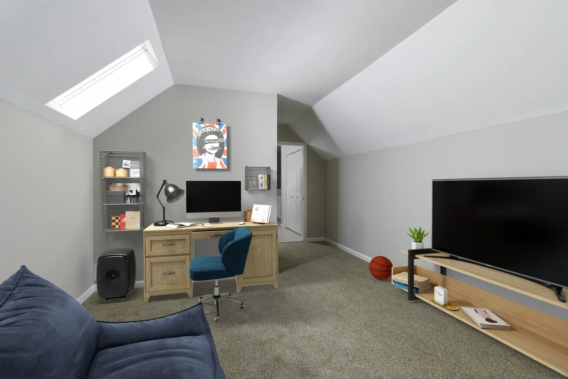 Attic-style home office in an apartment with a desk, computer monitor, chair, shelves, and a large TV at Springhouse Townhomes in Allentown, PA.