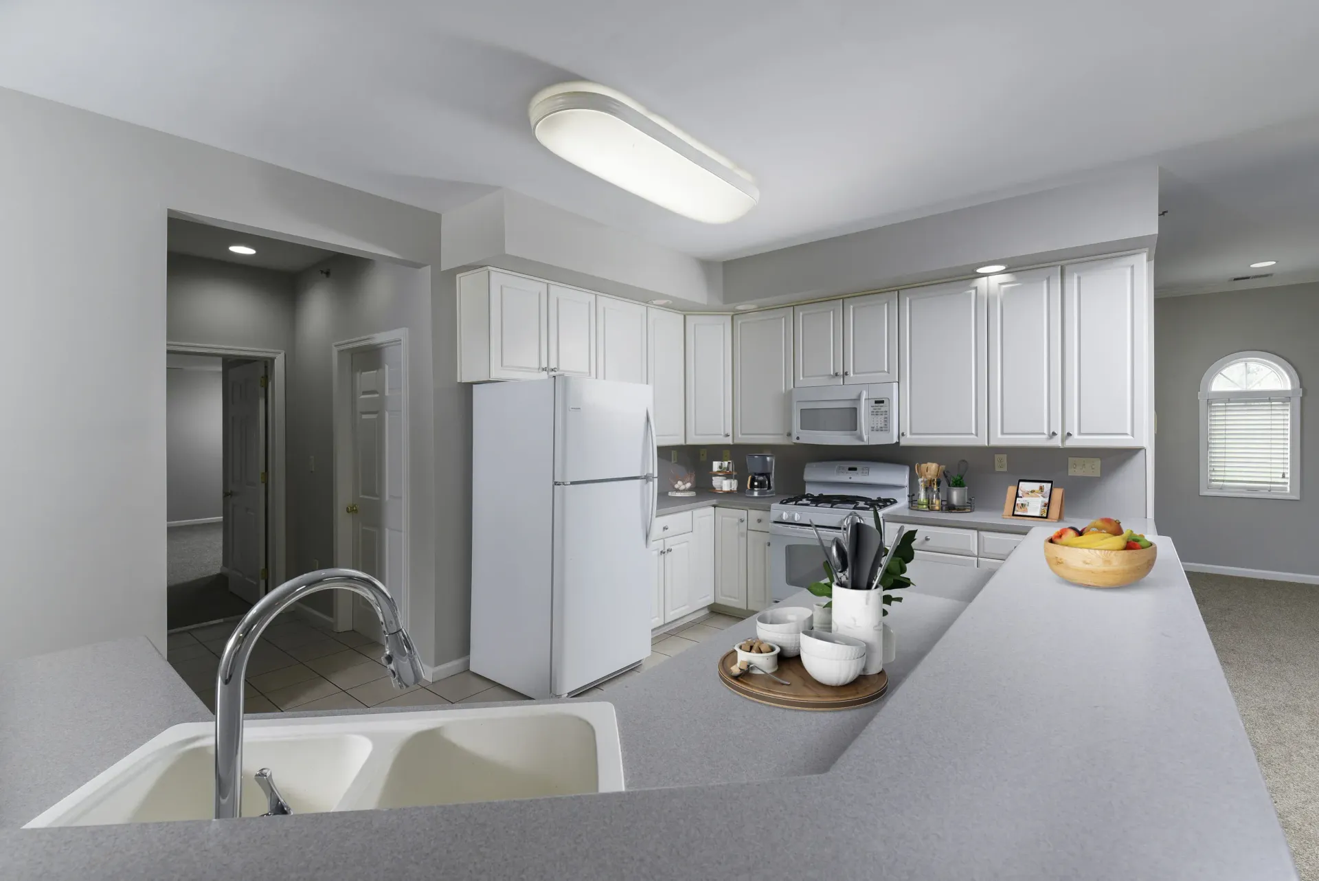 Open-concept apartment kitchen with white cabinets, island, sink, and stainless appliances at Springhouse Townhomes in Allentown, PA.
