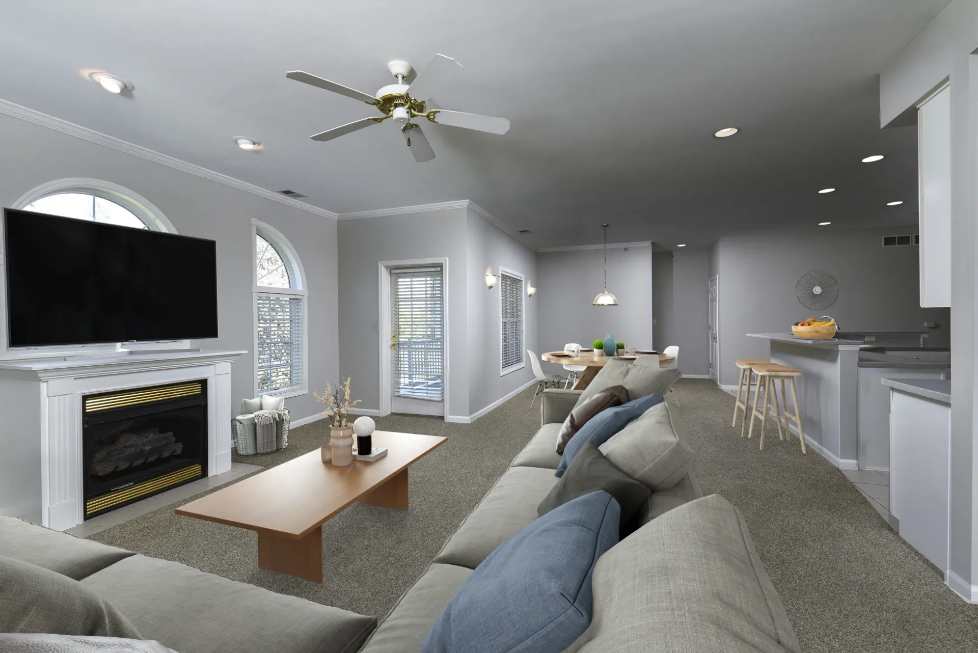 Open-concept living room with gray walls, a fireplace, large windows, and a kitchen island at Springhouse Townhomes in Allentown, PA.