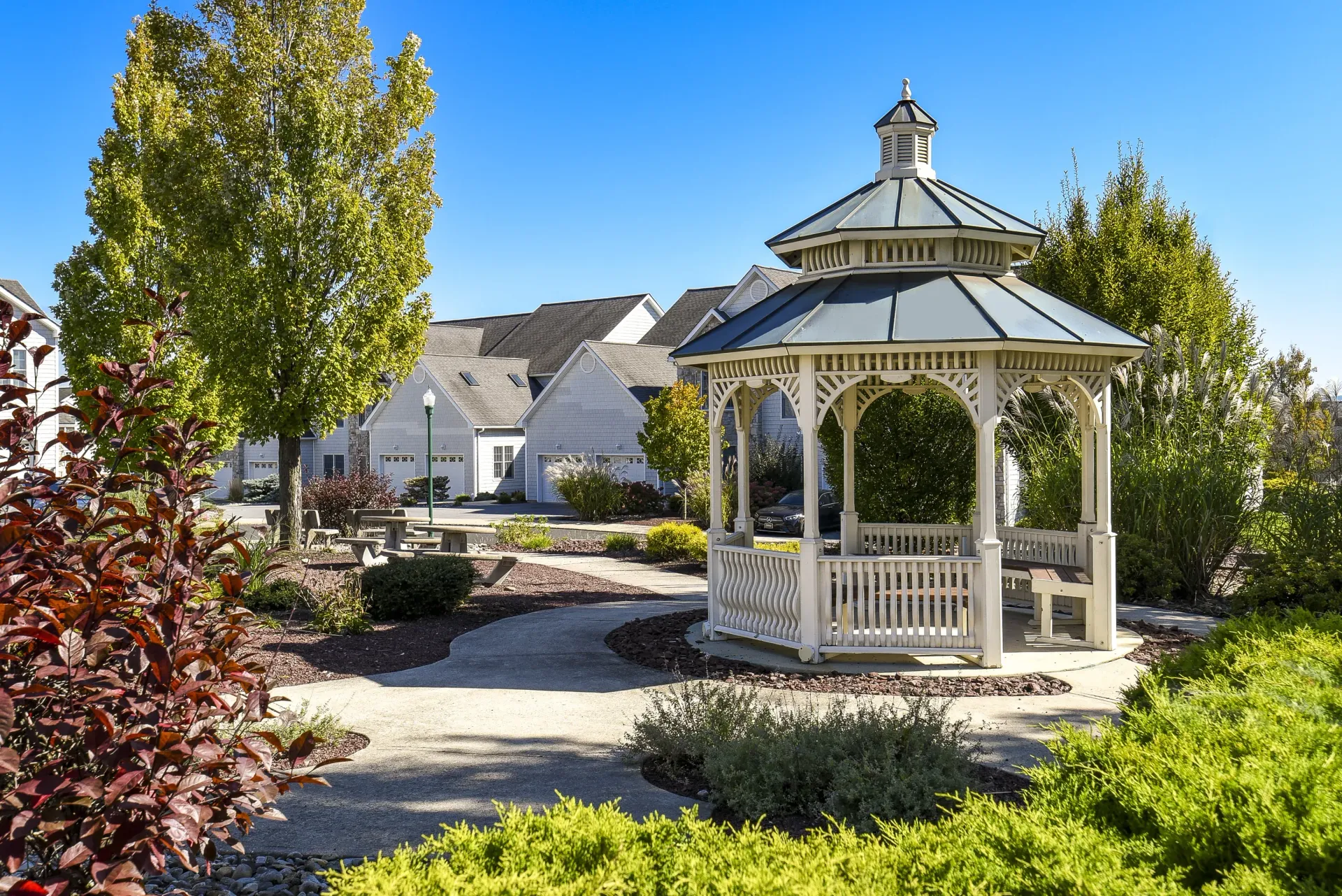 Gazebo in a landscaped apartment complex courtyard with trees and benches at Springhouse Townhomes in Allentown, PA.