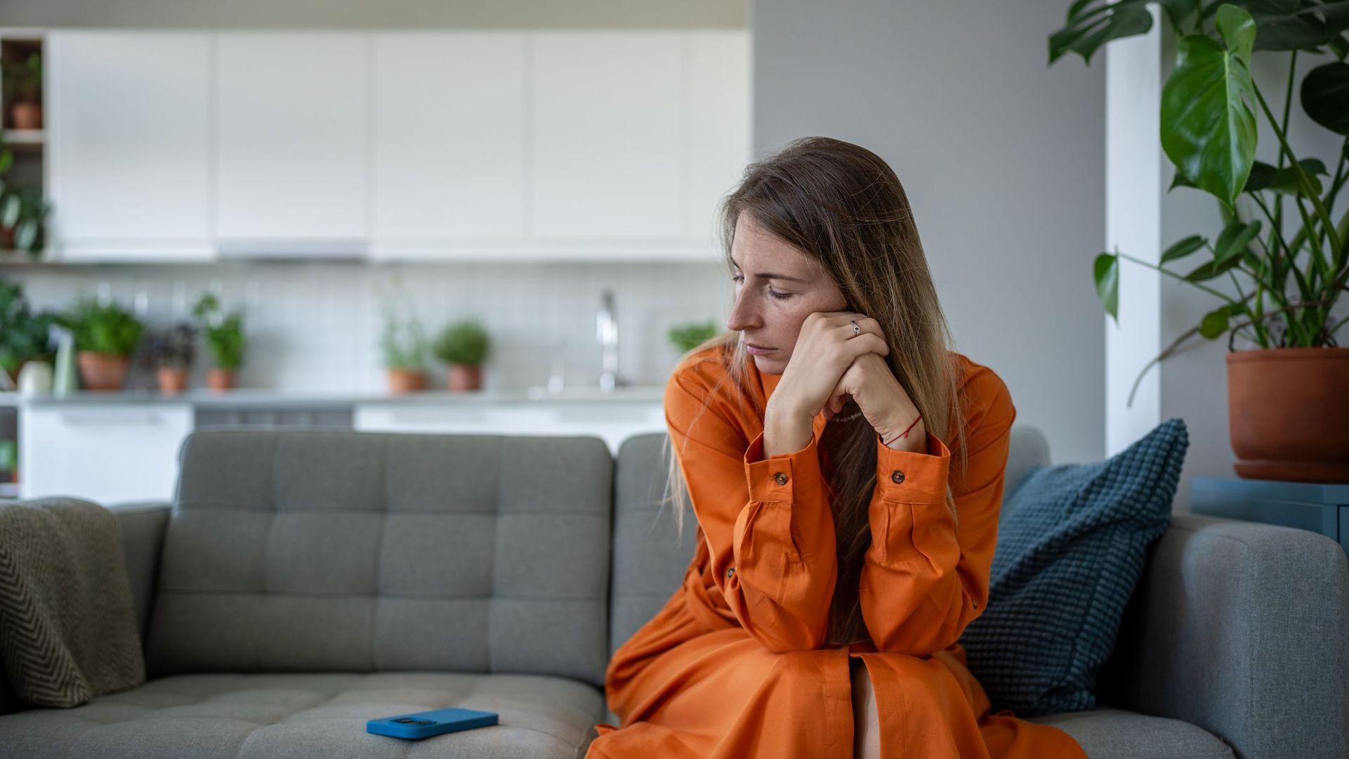 woman sitting on a couch looking sad and overwhelmed